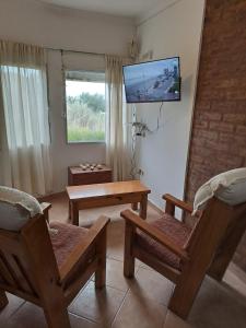 sala de estar con sillas y TV en la pared en Tranquilo duplex frente al mar, en Monte Hermoso