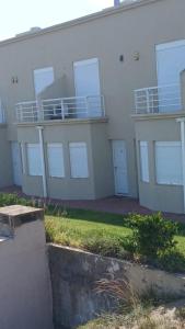 Un edificio blanco con balcones a los lados. en Tranquilo duplex frente al mar, en Monte Hermoso