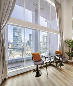 a room with a table and chairs in front of a large window at Two-Story Loft with a High-rises view and Rooftop Deck in Vancouver +53 photos