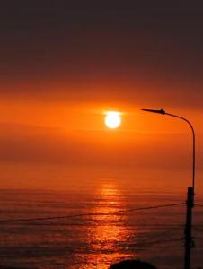 a sunset over the ocean with a street light at Apartamento en San Miguel hermosa vista al mar in Lima
