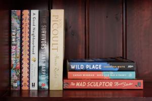 a group of books sitting on a shelf at Charming 3-Bedroom Home with Sunroom & Parking in Kings Park