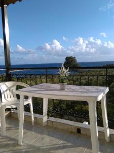 a white table and a chair on a balcony with the ocean at Kastraki Studios in Stoupa