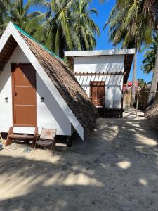 a small white building with a thatch roof at Tatak Balabac Beach Camp in Olorga +34 photos
