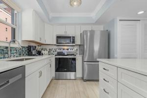 a kitchen with white cabinets and a stainless steel refrigerator at Beach Villas 706 Top-Floor Condo with Gulf Views, Pool condo in Fort Myers Beach