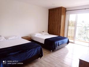 El PeñolにあるVilla Maruのベッドが2つと大きな窓がある寝室 +27枚の写真