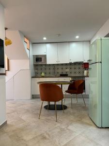a kitchen with white cabinets and a table and chairs at Casa Rosa in Setúbal