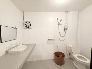 a white bathroom with a toilet and a sink at Inn Convenience in Coron