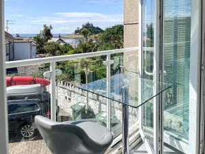a balcony with a chair and a glass table at Seaglass in Marazion
