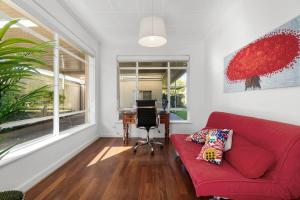 a living room with a red couch and a desk at The Spacious & Elegant Vacation Haven - Glenside in Glenunga