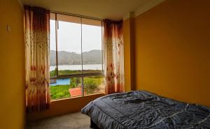 a bedroom with a bed and a large window at Hotel TALF in Cajamarca