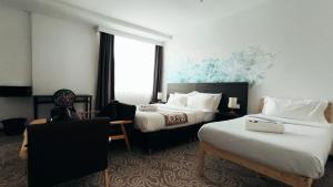 una habitación de hotel con dos camas y una silla en Natol Hotel, en Kuching