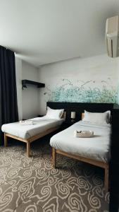 Dos camas en una habitación con un cuadro en la pared. en Natol Hotel, en Kuching