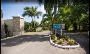 La Grande PrincessePristine Resort Beach的棕榈树道路中间的一个标志