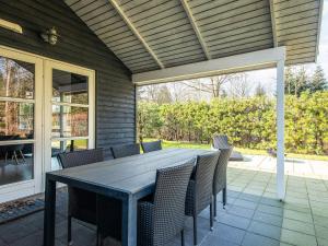 a wooden table and chairs on a patio at 6 person holiday home in Ansager in Ansager +34 photos