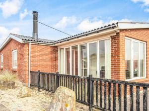 a red brick house with a black fence at 8 person holiday home in Ulfborg in Ulfborg