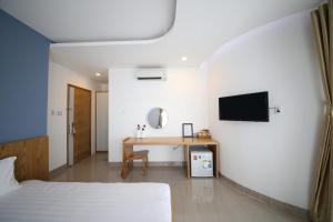 a bedroom with a bed and a desk with a tv at Sailing Hotel Phú Quốc in Phú Quốc