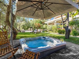 a hot tub in a yard with an umbrella at Serene Studio by the Sea in Banjol