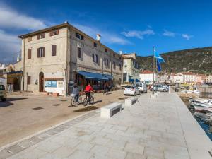 a group of people riding bikes on a street next to a building at Holiday Home near Beach in Croatia in Cres