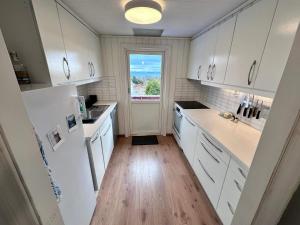 una cucina con mobili bianchi e una grande finestra di 6 person holiday home in KLOKKARVIK a Klokkarvik