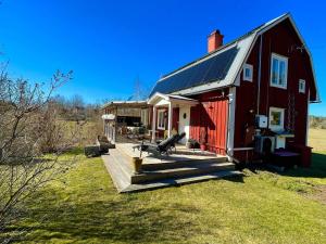 a red barn with a porch and a deck at 6 person holiday home in VIMMERBY in Vimmerby