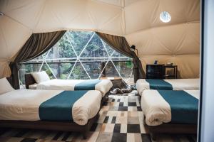 four beds in a room with a large window at エメラルドの森 in Izunokuni +58 photos