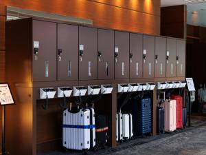 a row of suitcases lined up against a wall in an airport at JR Kyushu Hotel Kagoshima in Kagoshima