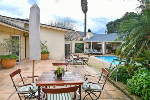 Un patio con mesas y sillas junto a una piscina. en The Protea Apartment no01, en Franschhoek
