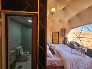 a bedroom with a bed and a bathroom with a window at Wadi Rum star in Wadi Rum