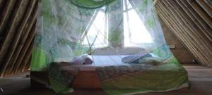a bedroom with a bed with a window with curtains at Bamboo Hut Alpha Hotel in Maluk