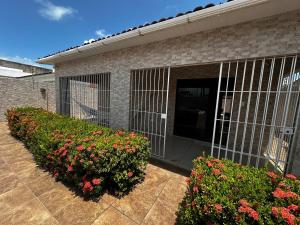a building with a gate and flowers in front of it at Enseada dos corais - Cabo de Santo Agostinho com piscina grande in Cabo de Santo Agostinho