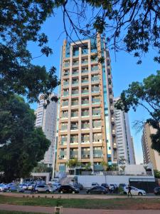 a tall building with cars parked in a parking lot at Belissímo in Brasília