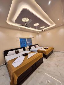 two beds in a room with a ceiling at Reddys Guest House in Hampi