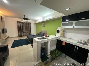 a room with a kitchen and a living room with a couch at De Viana Apartment Homestay in Kota Bharu