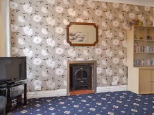 sala de estar con chimenea y papel pintado con motivos florales en Comyn, en Bridlington