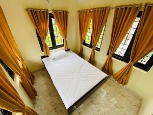 a bed in a room with two windows at White Legacy Ooty - Families Only in Ooty +1 photo