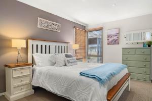 Un dormitorio con una cama con una manta azul encima. en Outlook Escape by Ready Set Stay - BYO LINEN & TOWELS, en Cowes 15 fotos más
