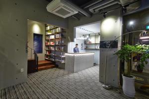 Un homme debout à un comptoir dans une pièce avec des livres dans l'établissement Hotel The May, à Gwangju