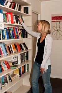 una mujer está buscando un estante de libros en Seagulls Guesthouse, en Mount Maunganui
