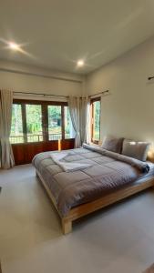 a large bed in a room with windows at 2-Bedroom Maduea Wan House in Ko Phangan