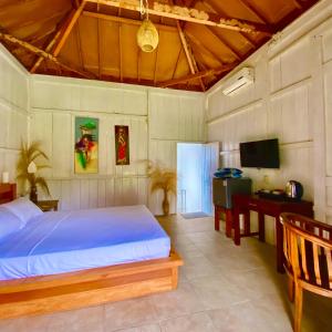 a bedroom with a bed and a desk and a television at Lotus & Teak Villas in Dalung