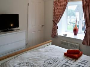 Schlafzimmer mit einem Bett, einem TV und einem Fenster in der Unterkunft Pottergate Cottage in Wroxham