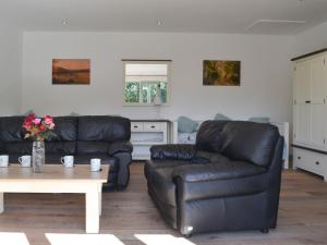un soggiorno con 2 divani in pelle nera e un tavolo di East Croft Barn a Halwill