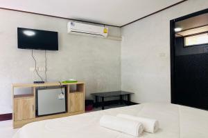 ein Schlafzimmer mit einem weißen Bett und einem TV an der Wand in der Unterkunft Ton Hom Pool Party in Hua Hin