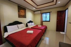 zwei Betten in einem Zimmer mit roten Laken und weißen Kissen in der Unterkunft Ton Hom Pool Party in Hua Hin