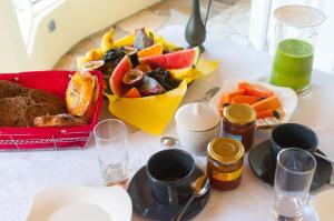 - une table avec une assiette de nourriture et un bol de fruits dans l'établissement La Résidence des Caféiers - Le Tampon, à Le Tampon