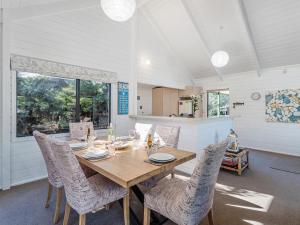 a dining room with a wooden table and chairs at Beaumont Beach Retreat - Pauanui Holiday Home in Pauanui