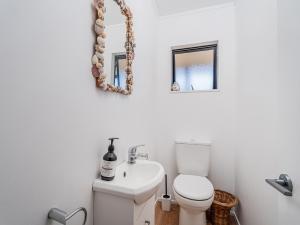 a bathroom with a white toilet and a sink at Beaumont Beach Retreat - Pauanui Holiday Home in Pauanui +25 photos
