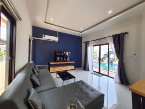 un salon avec un canapé et un mur bleu dans l'établissement Morning Glory Pool Villa Chaam-Huahin, à Sathani Huai Sai Tai