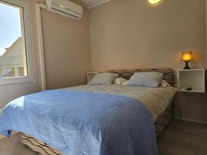 a bedroom with a bed with a blue blanket and a window at Bed and Breakfast BLUE in BLUE, Room GREEN + in Komiža