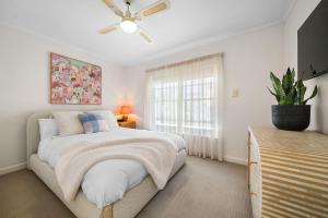 a white bedroom with a bed and a window at Glenelg Hideaway Bliss in Glenelg